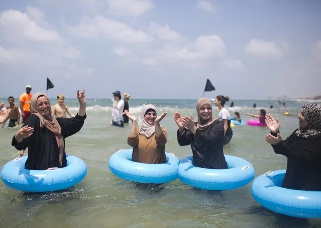 A picture made available on 10 August 2016 shows a group of Palestinian from the West Bank city of Hebron singing and enjoying the water at the beach of Tel Aviv for the first time, Israel, 08 August 2016. A group of humanitarian Israeli women called in Arabic “Min Al Baher” (from the sea) voluntarily arranges authorizations and transportation for Palestinians families that live in the West Bank to cross into Israel in order to visit the sea for the first time. (Photo by Abir Sultan/EPA)