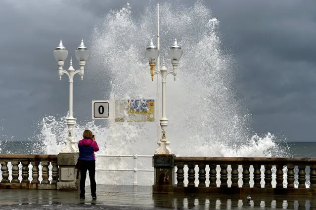 A woman takes pictures as a huge wave crashes against the promenade at San Lorenzo beach in Gijon, Spain December 14, 2017. (Photo by Eloy Alonso/AFP Photo)