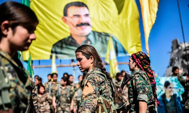 Female fighters of the Syrian Democratic Forces (SDF) gather during a celebration at the iconic Al- Naim square in Raqa on October 19, 2017, after retaking the city from Islamic State (IS) group fighters. The SDF fighters flushed jihadist holdouts from Raqa' s main hospital and municipal stadium, wrapping up a more than four- month offensive against what used to be the inner sanctum of IS' s self- proclaimed “caliphate”. (Photo by Bulent Kilic/AFP Photo)
