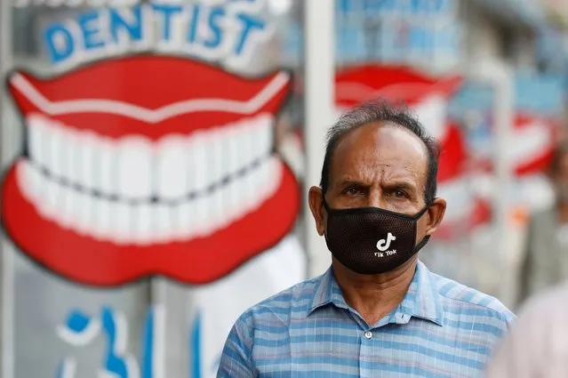 A man wears a protective face mask with the TikTok logo as he walks along dental shops, as the outbreak of the coronavirus disease (COVID-19) continues, in Karachi, Pakistan on July 14, 2020. (Photo by Akhtar Soomro/Reuters)