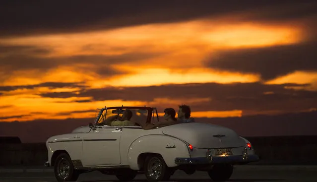 Tourists ride a vintage American convertible during sunset on the Malecon in Havana, Cuba, Wednesday, September 30, 2015. (Photo by Desmond Boylan/AP Photo)