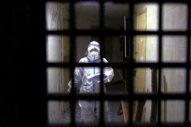 A pandemic prevention worker in a protective suit approaches an apartment in a building that went into lockdown as coronavirus disease (COVID-19) outbreaks continue in Beijing, on December 2, 2022. (Photo by Thomas Peter/Reuters)