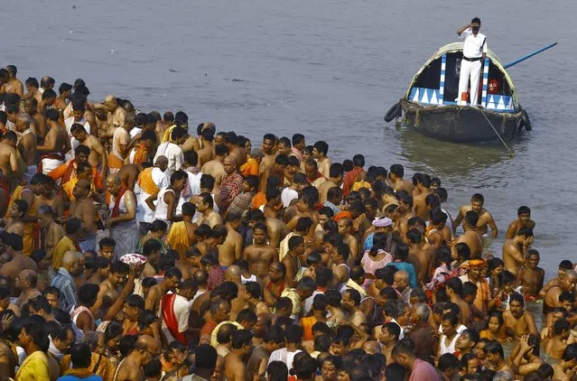 A policeman (top) keeps watch from a boat as Hindus gather to perform prayers on the banks of the Ganges river on the holy day of Mahalaya in Kolkata, India, October 12, 2015. (Photo by Rupak De Chowdhuri/Reuters)