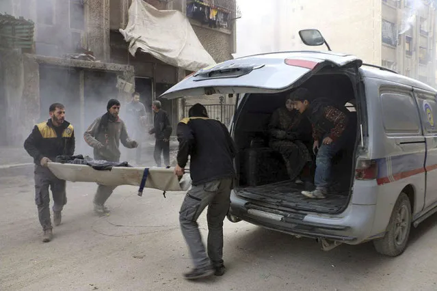 This photo provided by the Syrian Civil Defense group known as the White Helmets, shows Civil Defense workers carrying an survivor on a stretcher after airstrikes hit a rebel-held suburb near Damascus, Syria, Monday, February 5, 2018. Syrian opposition activists said more than one dozen people killed in new airstrikes. (Photo by Syrian Civil Defense White Helmets via AP Photo)