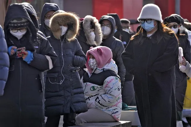 Residents wearing face masks line up in freezing cold temperatures to buy Lunar New Year deserts in Beijing, Tuesday, January 17, 2023. (Photo by Andy Wong/AP Photo)