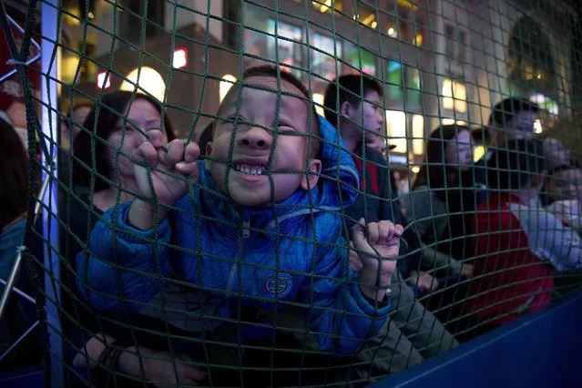 A Chinese boy bites the net as he watches a Youth Tackle Football game at a National Football League publicity event held in Beijing, China, Friday, October 23, 2015. The NFL has been aggressively promoting football in China hoping to take advantage of rising income and growing taste for exotic foreign sports. (Photo by Ng Han Guan/AP Photo)