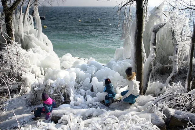 Children play in middle of ice covers rocks and plants on the frozen shores of the Lake of Neuchatel, in Boudry, Switzerland, 28 February 2018. A cold spell has reached central and eastern Europe with temperatures far below zero. Media reports state that extreme cold weather is forecast to hit many parts of Europe with temperatures plummeting to a possible ten year low. (Photo by Laurent Gillieron/EPA/EFE)