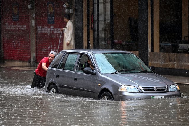 A man pushes a car through a flooded street during heavy monsoon rains in Rawalpindi on July 17, 2025. Monsoon rains in Pakistan have been linked to more than 110 deaths including dozens of children since they arrived in late June, according to government figures released on July 14. (Photo by Aamir Qureshi/AFP Photo)
