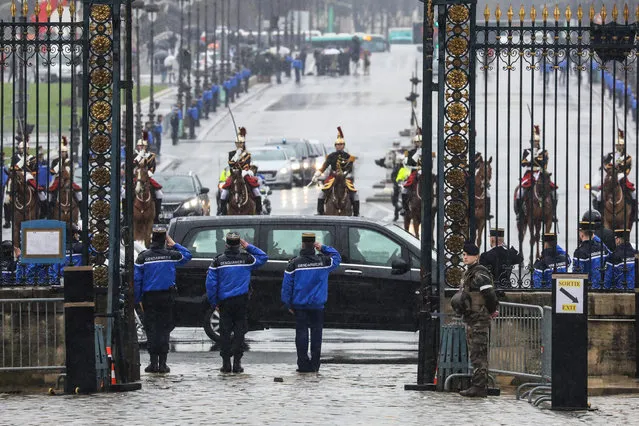 Gendarmes stand at attention as the convoy of French Republican Guards escorting the coffin of late Lieutenant Colonel Arnaud Beltrame transported by car (C) during a funeral procession arrives for a national ceremony on March 28, 2018 at the Hotel des Invalides in Paris. France honours during a national ceremony on March 28 a heroic policeman who died offering himself as a hostage in a jihadist attack. Beltrame, 44, was the fourth and final victim in the shooting spree on March 23 in the southwestern towns of Carcassonne and nearby Trebes. (Photo by Ludovic Marin/AFP Photo)