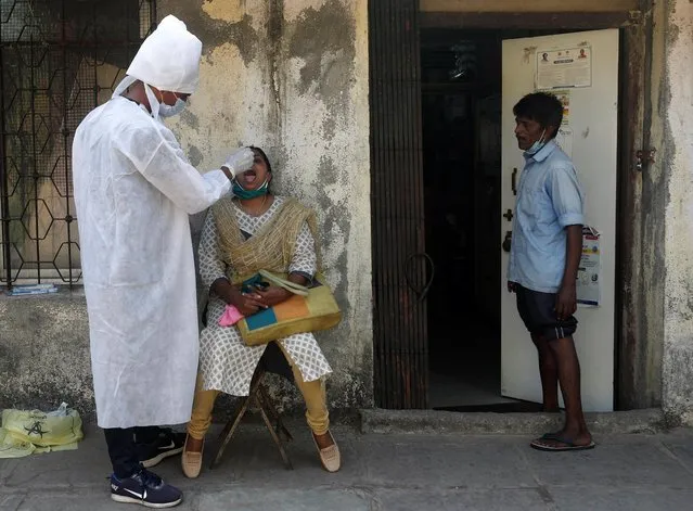 A health worker in personal protective equipment (PPE) collects a swab sample from a woman during a testing campaign for the coronavirus disease (COVID-19), at a clinic in Mumbai, India, November 24, 2020. (Photo by Francis Mascarenhas/Reuters)