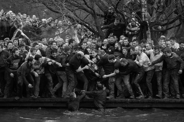 Royal Shrovetide football: Members of opposing teams, the Up’ards and Down’ards, grapple for the ball during the historic, annual Royal Shrovetide Football Match in Ashbourne, Derbyshire, UK, February 28, 2017. The game is played between hundreds of participants in two eight-hour periods on Shrove Tuesday and Ash Wednesday (the day preceding and the day marking the start of Christian Lent). The two teams are determined by which side of the River Henmore players are born: Up’ards are from north of the river; Down’ards, south. Players score goals by tapping the ball three times on millstones set into pillars three miles apart. There are very few rules apart from an historic stipulation that players may not murder their opponents, and the more contemporary requirement that the ball must not be transported in bags, rucksacks, or motorized vehicles. Royal Shrovetide Football is believed to have been played in Ashbourne since the 17th century. (Photo by Oliver Scarff/Agence France-Presse/World Press Photo)