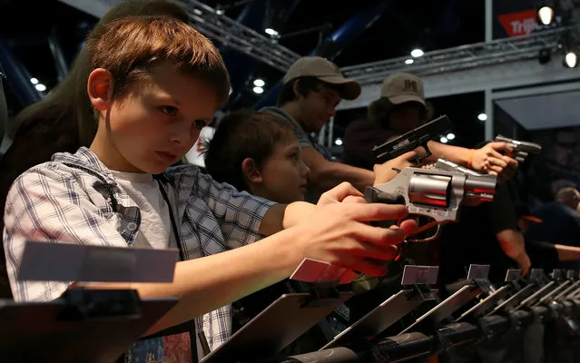 An young attendee inspects a handgun during the 2013 NRA Annual Meeting and Exhibits at the George R. Brown Convention Center on May 4, 2013 in Houston, Texas. More than 70,000 peope are expected to attend the NRA's 3-day annual meeting that features nearly 550 exhibitors, gun trade show and a political rally. (Photo by Justin Sullivan/AFP Photo)