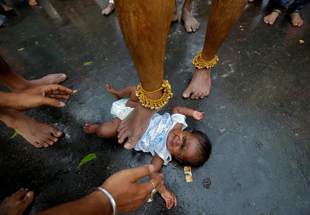 A Hindu holy man touches an infant with his foot as part of a ritual to bless her during a religious procession to mark Bhel Bhel festival dedicated to Hindu goddess Muthumariamman in Bandel town in the eastern state of West Bengal, India, April 6, 2018. (Photo by Rupak De Chowdhuri/Reuters)