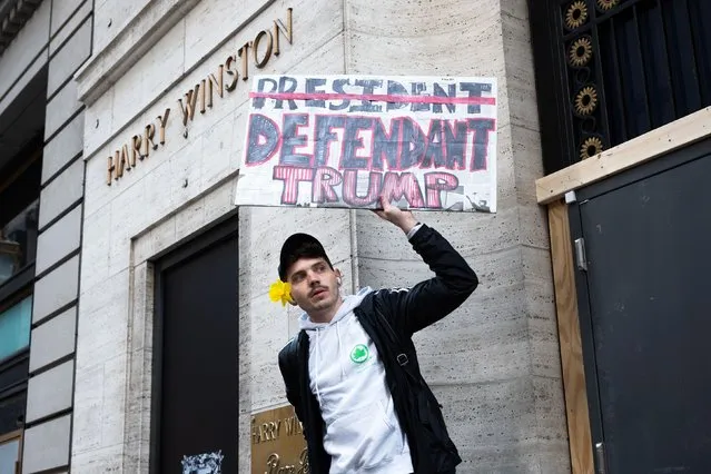 Lucas Camp of Astoria holds a sign reading ‘Defendant Trump’ outside Trump Tower Tuesday, April 4, 2023 in Manhattan. (Photo by Joe Lamberti for The Washington Post)