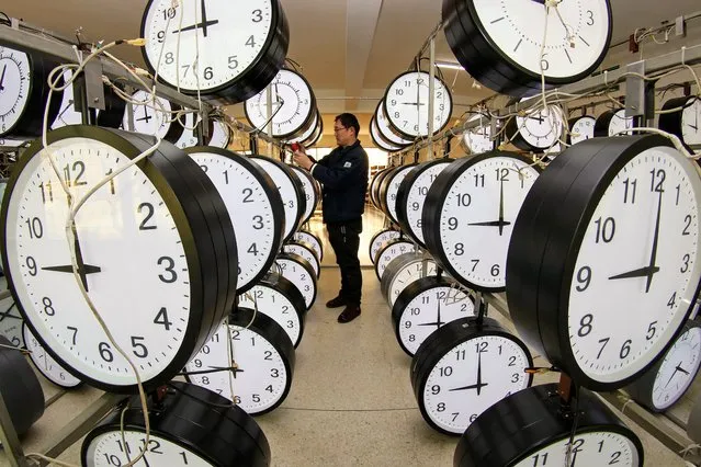 A technician checks hanging clocks at a workshop of a clock company in Yantai, in eastern China's Shandong province on December 15, 2020. (Photo by AFP Photo/China Stringer Network)