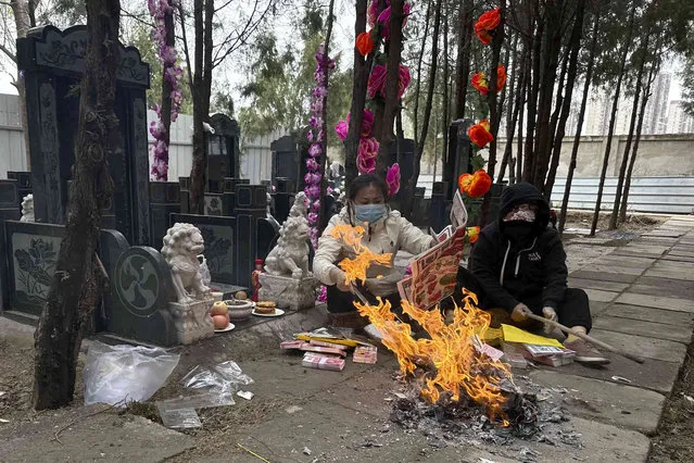 Residents burn papers with images of home appliances, cars and fruits for the deceased during Qingming festival also known as Tomb Sweeping Day when family members visit their ancestral graves to clean up and burn offerings in Beijing, Wednesday, April 5, 2023. (Photo by Ng Han Guan/AP Photo)