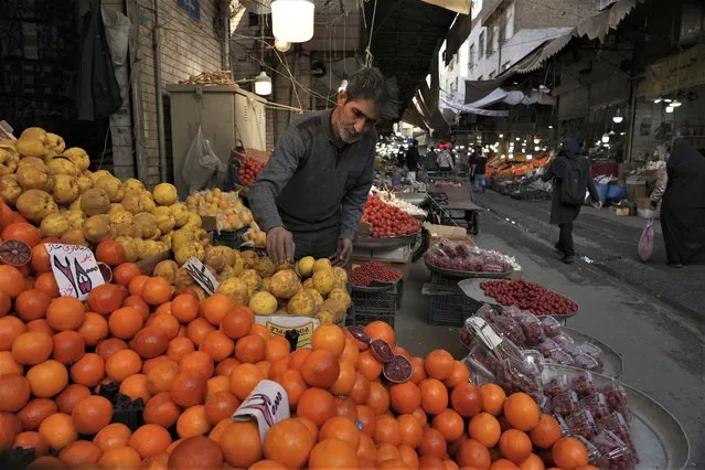 A fruit seller arranges his fruits at a local market in Tehran, Iran, ahead of the Persian new year, known as Nowruz, Wednesday, March 15, 2023. Iran's bazaars are packed ahead of the Persian New Year next week, but there's little holiday cheer as customers survey the soaring prices of meat and holiday treats, wondering if they can afford either. (Photo by Vahid Salemi/AP Photo)