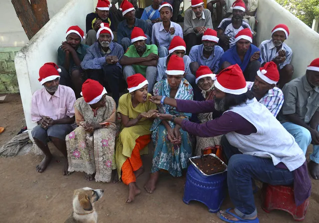 George Rakesh Babu, right, founder of Good Samaritans India, a non-government organization feeds food to a homeless person at a shelter to celebrate Christmas on the outskirts of Hyderabad, India, Friday, December 25, 2020. (Photo by Mahesh Kumar A./AP Photo)