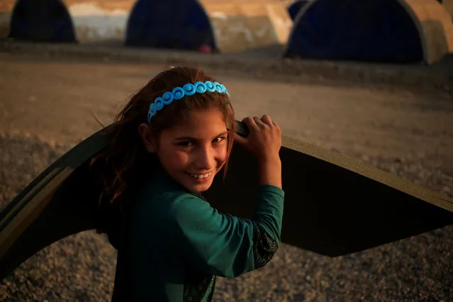 A newly internally displaced girl smiles as she carries foam mattresses upon her arrival at Al Khazar camp near Hassan Sham, east of Mosul, Iraq October 26, 2016. (Photo by Zohra Bensemra/Reuters)