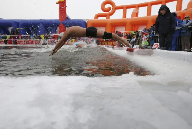 Swimmers dive into a pool carved into thick ice covering the Songhua River during the Harbin Ice Swimming Competition in the northern city of Harbin, Heilongjiang province January 5, 2015. (Photo by Kim Kyung-Hoon/Reuters)