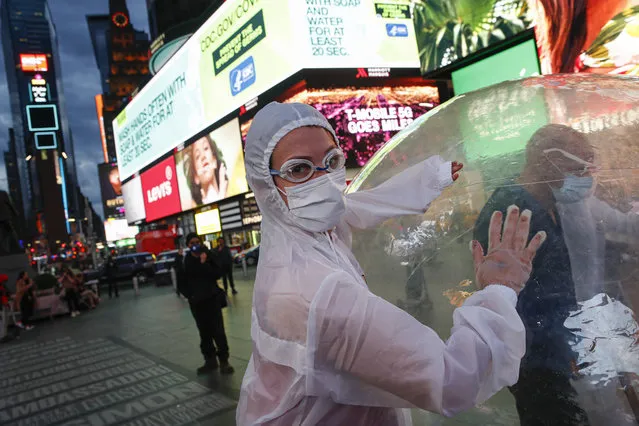 Artists perform under a billboard displaying information on COVID-19 in a sparsely populated Times Square, Friday, March 20, 2020, in New York. New York Gov. Andrew Cuomo is ordering all workers in non-essential businesses to stay home and banning gatherings statewide. “Only essential businesses can have workers commuting to the job or on the job”, Cuomo said of an executive order he will sign Friday. Nonessential gatherings of individuals of any size or for any reason are canceled or postponed. (Photo by John Minchillo/AP Photo)