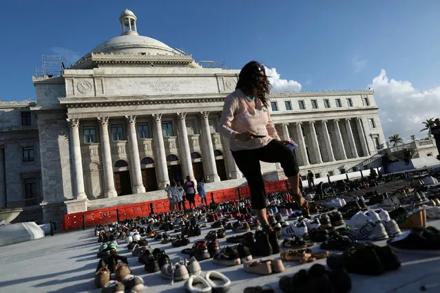 A woman walks among hundreds of pairs of shoes displayed at the Capitol to pay tribute to Hurricane Maria's victims after a research team led by Harvard University estimated that 4,645 people lost their lives, a number not confirmed by the government, in San Juan, Puerto Rico June 1, 2018. (Photo by Alvin Baez/Reuters)
