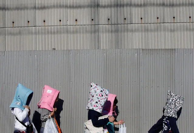 School children wearing padded hoods to protect them from falling debris make their way to an evacuation shelter on a hill during a tsunami simulation drill ahead of World Tsunami Awareness Day at Futaba elementary school in Choshi, Chiba Prefecture, Japan, November 4, 2016. (Photo by Kim Kyung-Hoon/Reuters)