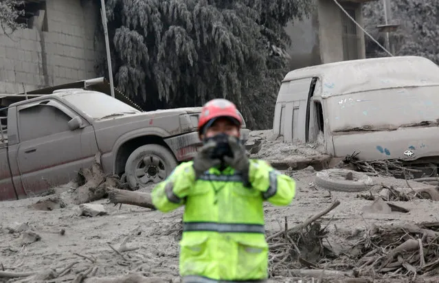 Vehicles damaged by an eruption from Fuego volcano are seen beside a firefighter in the community of San Miguel Los Lotes in Escuintla, June 4, 2018. (Photo by Luis Echeverria/Reuters)