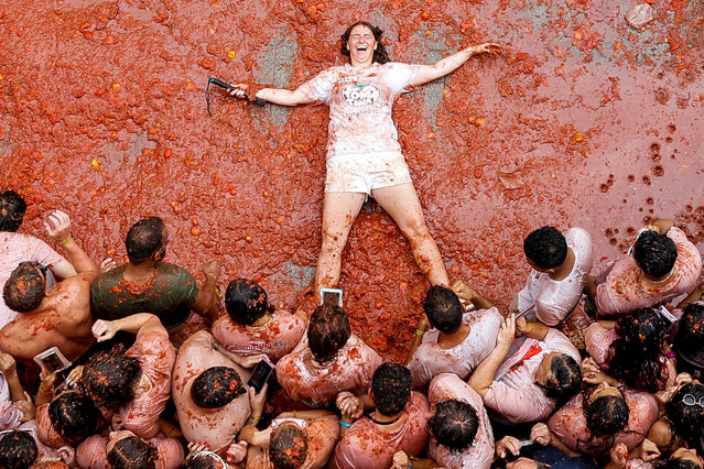 A participant lies in tomato pulp, as people attend the annual food fight festival “La Tomatina” in Bunol, near Valencia, Spain on August 28, 2024. (Photo by Eva Manez/Reuters)