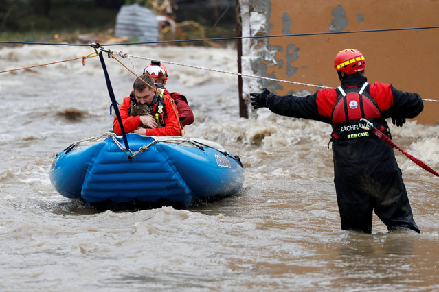A man holds a cat as he is aided by rescuers on a flooded street, following heavy rainfall in Jesenik, Czech Republic, on September 15, 2024. (Photo by David W. Cerny/Reuters)