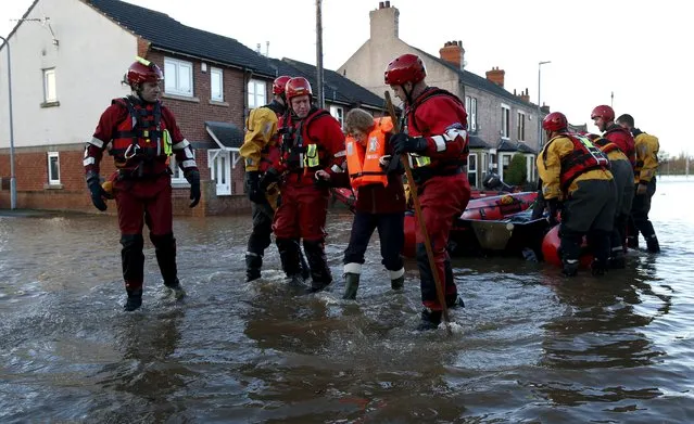 Rescue workers help a woman through a flooded residential street in Carlisle, Britain December 6, 2015. (Photo by Phil Noble/Reuters)