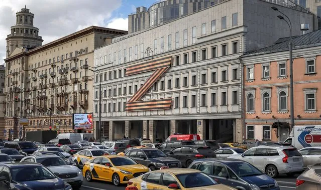 Cars stuck in traffic in front of a theatre building decorated with the letter Z in Moscow, Russia, 30 March 2022. The letter Z has been used by Russian forces as an identifying sign on their vehicles in Ukraine. On 24 February Russian troops had entered Ukrainian territory in what the Russian president declared a “special military operation”, resulting in fighting and destruction in the country, a huge flow of refugees, and multiple sanctions against Russia. (Photo by Yuri Kochetkov/EPA/EFE)