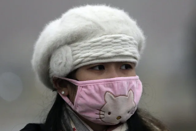 In this December 1, 2015 photo, a woman wears a mask to protect herself from pollutants near Tiananmen Gate on a heavily polluted day in Beijing. (Photo by Andy Wong/AP Photo)