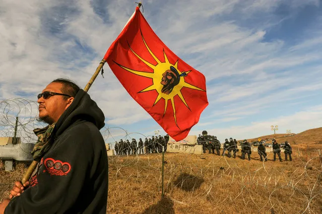 A protesters flies a flag during a stand off with police during a protest of the Dakota Access pipeline near the Standing Rock Indian Reservation near Cannon Ball, North Dakota November 6, 2016. (Photo by Stephanie Keith/Reuters)