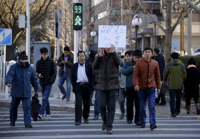 Tian Honglei (C), a migrant worker from Henan province, holds a placard as he marches with his fellow workers along a main street to protest against a construction site and demand their salaries, in central Beijing, China, December 10, 2015. A total of 32 construction workers took to the street on Thursday to demand a construction site in Xianghe county of Hebei province to pay what they say are their delayed salaries worth about a total of 660,000 yuan (102,510 USD). (Photo by Jason Lee/Reuters)