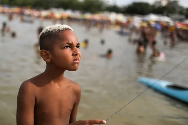A boy flies a kite at an artificial pond known as Piscinao de Ramos, or big pool, amid the coronavirus disease (COVID-19) outbreak, in the northern suburbs of Rio de Janeiro, Brazil on January 31, 2021. (Photo by Pilar Olivares/Reuters)
