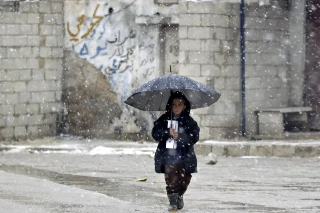 A child walks under an umbrella during a snow storm in Kvromh village in Idlib province January 15, 2015. (Photo by Khalil Ashawi/Reuters)