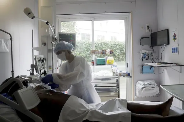 Nurse Stephanie Dias tends to a patient affected by COVID-19 virus in the ICU unit at the Ambroise Pare clinic in Neuilly-sur-Seine, near Paris, Friday, March 19, 2021. French Prime Minister Jean Castex announced new coronavirus restrictions as the number of COVID-19 patients in intensive care units spikes. (Photo by Thibault Camus/AP Photo)