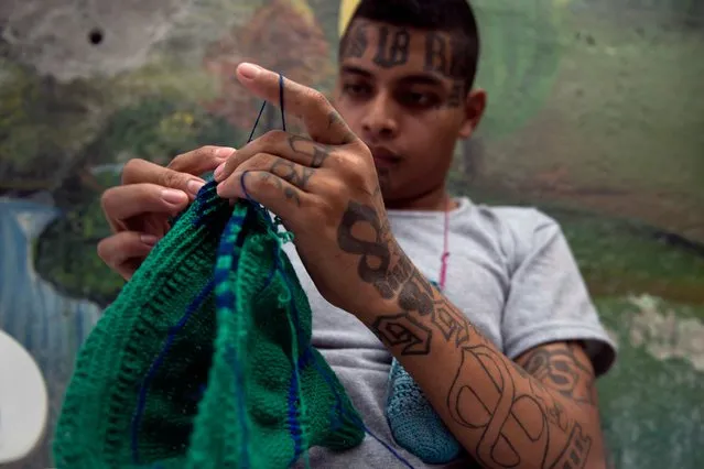 A former member of Barrio 18 gang, crochets a hat during a workshop at the prison of San Francisco Gotera, 161 km east of San Salvador on July 16, 2018. Members of two of the world's most feared gangs, El Salvador's Mara Salvatrucha and Barrio 18, prepare to reintegrate into society as they receive a range of classes in jail including DIY, music and knitting as part of a program known as “I Change”. (Photo by Oscar Rivera/AFP Photo)