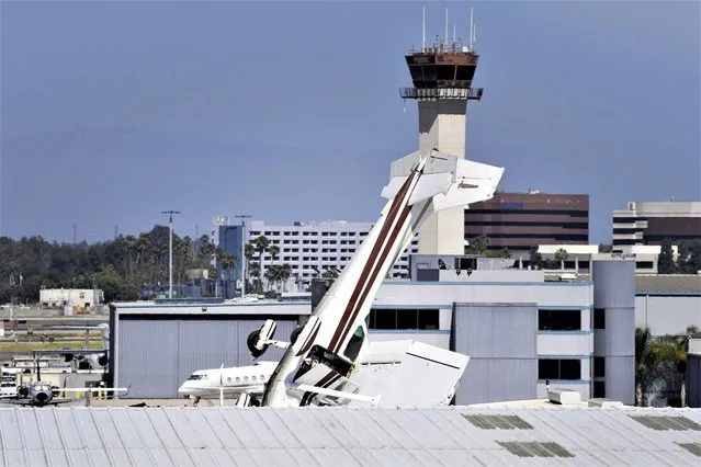 A Cessna plane sits nose-first after crashing into the roof of a hangar at Long Beach airport in California on July 11, 2023. The authorities say the pilot escaped with only minor injuries. (Photo by Brittany Murray/The Orange County Register via AP Photo)