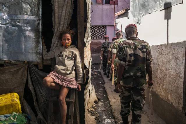 A child sit with her protective mask across her mouth and nose as members of the army patrol the streets of Antananarivo ordering citizens to go home as the Malagasy authorities declared a total weekend lockdown in the capital on April 24, 2021, to avoid the proliferation of Covid-19 which has caused many deaths in recent weeks. Madagascar said on April 23, 2021 it would receive a first lot of Covid-19 vaccines soon to fight a second wave that has overwhelmed health facilities. The Indian Ocean island nation is struggling with burgeoning infections with nearly 9,900 cases recorded over the past month, of which at least 194 have been fatal. (Photo by Rijasolo/AFP Photo)