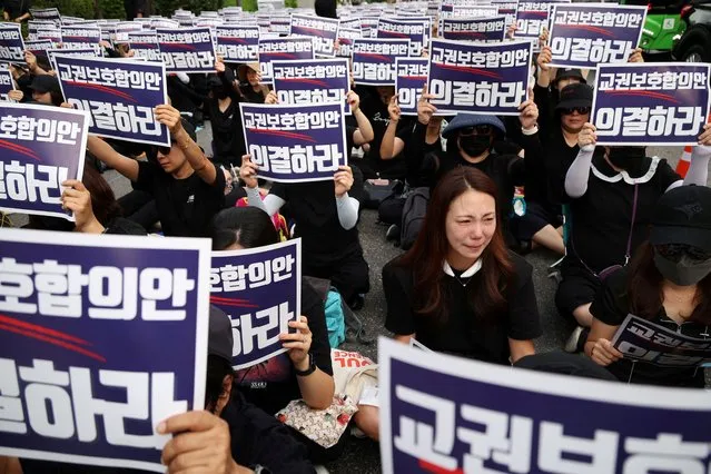 A South Korean teacher reacts as others chant slogans during a protest to demand better protection of their rights, the normalization of public education and to mourn a young teacher found dead in July in an apparent suicide, in Seoul, South Korea, September 4, 2023. The signs read “Vote for an agreement on the protection of teachers' rights”. (Photo by Kim Hong-Ji/Reuters)