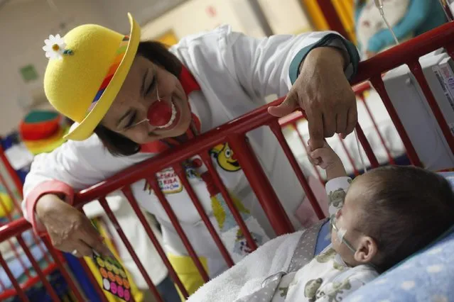 A baby grabs the finger of a member of “Laughter Doctors of Ciudad Juarez” as she performs at a children's hospital in Ciudad Juarez March 11, 2015. (Photo by Jose Luis Gonzalez/Reuters)