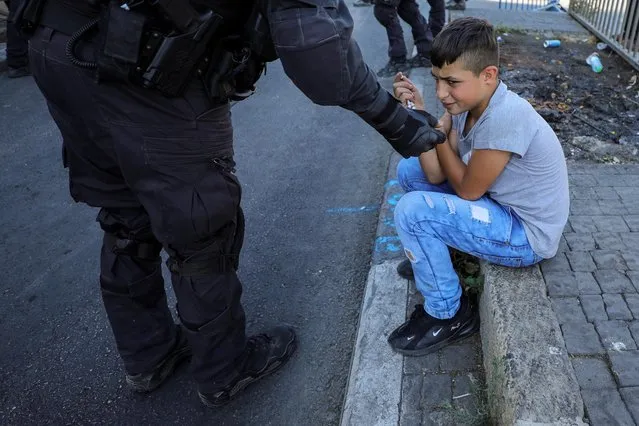 A Palestinian boy reacts as he is asked by an Israeli police officer to leave the area amid tension ahead of a flag-waving procession by far-right Israeli groups, at Jerusalem's Old City,  June 15, 2021. (Photo by Ammar Awad/Reuters)