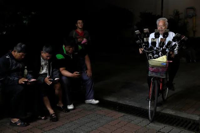 Taiwanese Chen San-yuan, 70, known as “Pokemon grandpa”, rides his bicycle as he plays the mobile game “Pokemon Go” by Nintendo, near his home with 15 mobile phones, in New Taipei City, Taiwan on November 12, 2018. (Photo by Tyrone Siu/Reuters)