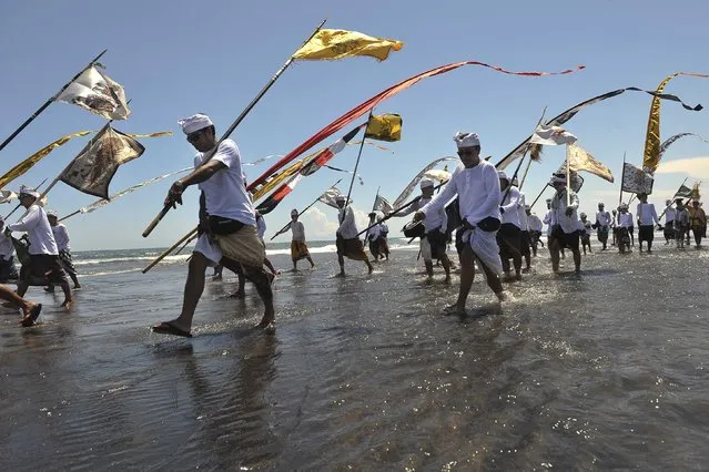 Balinese Hindus walk along the shore during the Melasti ceremony ahead of Nyepi day at Pererenan Beach on the Indonesian island of  Bali March 18, 2015 in this photo taken by Antara Foto. Nyepi is a day of silence to celebrate the Balinese new year, reserved for self-reflection, where people are not allowed to use lights, light fires, work, travel nor enjoy entertainment. (Photo by Nyoman Budhiana/Reuters/Antara Foto)