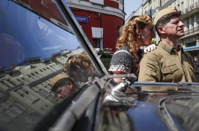 Participants of a historical reconstruction timed to coincide with the 80th anniversary of the beginning of mobilization in the USSR after the attack of Nazi Germany stand in front of a car from the period of the Second World War, in Moscow, Russia 24 June 2021. The reconstruction organized by the Liberal Democratic Party re-enacts one of the many episodes when thousands of volunteers rushed to the recruiting offices in Moscow. (Photo by Yuri Kochetkov/EPA/EFE)