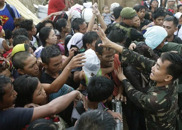 Typhoon survivors jostle to get a chance to board an evacuation flight on a C-130 military transport plane Tuesday, November 12, 2013, in Tacloban, central Philippines. (Photo by Bullit Marquez/AP Photo)