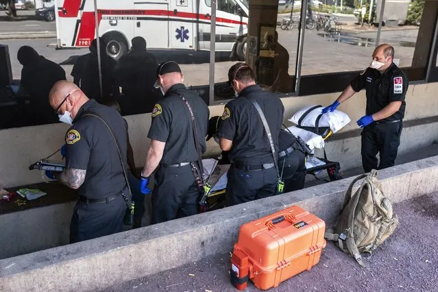Salem Fire Department paramedics and employees of Falck Northwest ambulance service respond to a heat exposure call during a heat wave, Saturday, June 26, 2021, in Salem, Ore. (Photo by Nathan Howard/AP Photo)