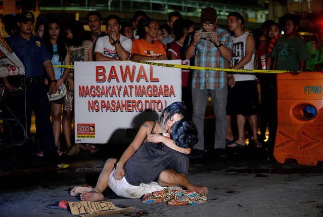 A woman hugs her husband, next to a placard which reads “I'm a pusher”, who was shot dead by an unidentified gunman in Manila on July 23, 2016. Philippine President Rodrigo Duterte swept to power in May on a promise to clampdown on drugs, and police have since confirmed killing nearly 200 people in a two-month crime blitz. There has also been a surge in killings by anti-drug vigilantes who leave victims' corpses on city streets wrapped in packaging tape with signs accusing them of being drug dealers. (Photo by Noel Celis/AFP Photo)